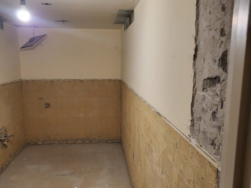 Shower stall with tile and damaged wall material removed