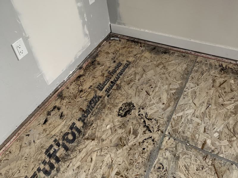 Flooring removed down to the subfloor along a water-damaged wall